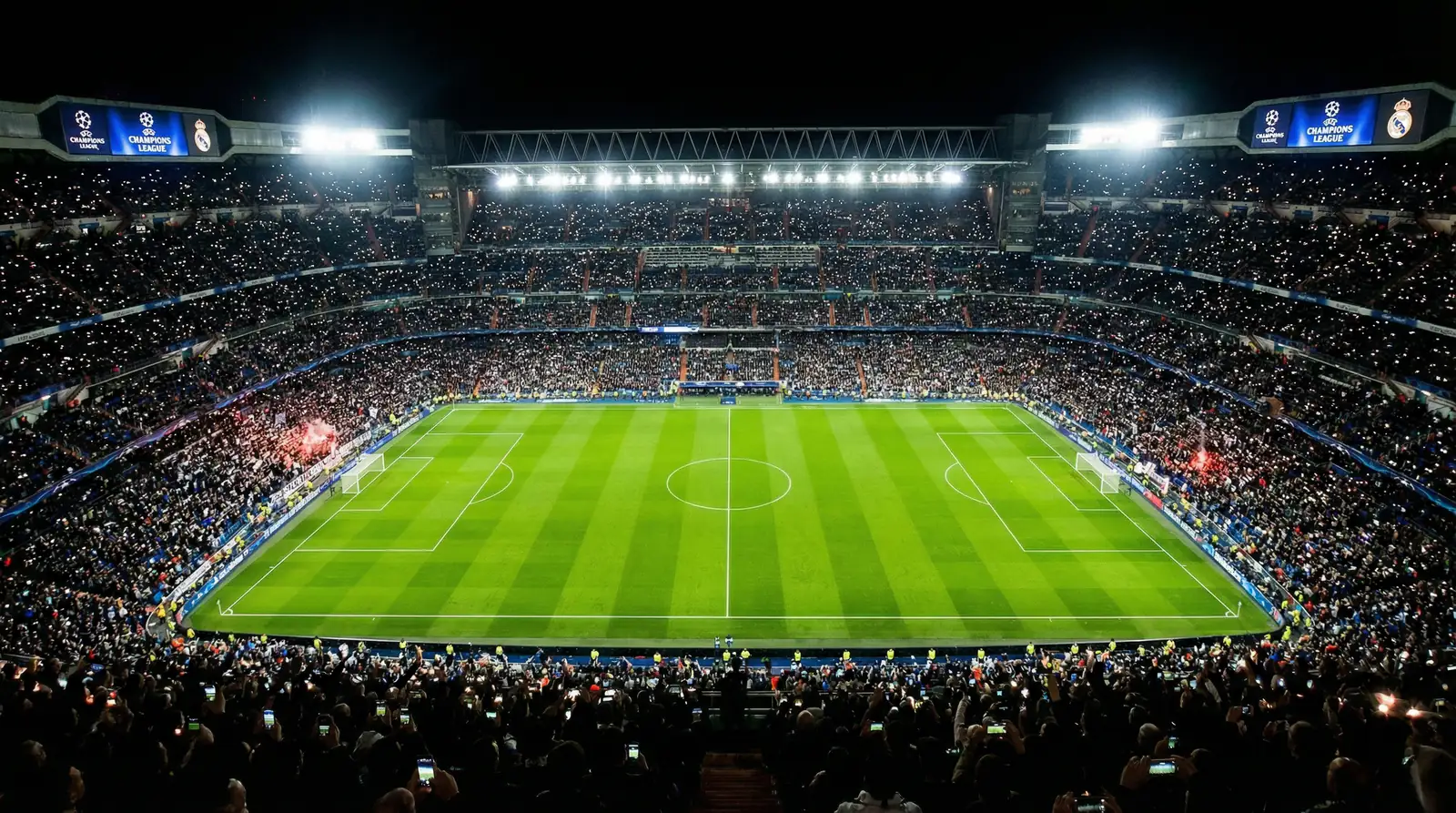 Estadio de fútbol europeo iluminado de noche con el césped verde brillante antes de un partido de Champions