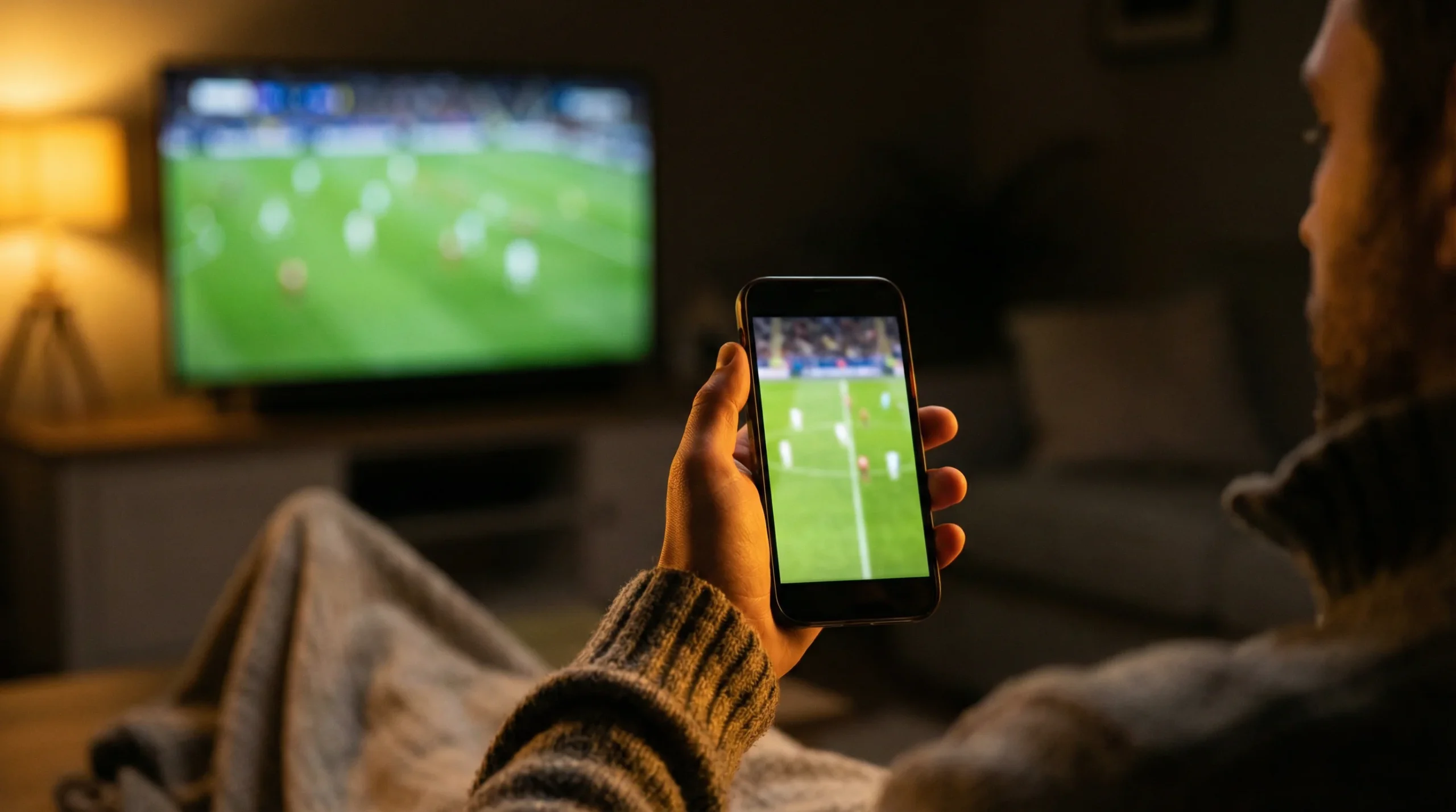 Mano de un hombre sobre un smartphone mostrando un partido de fútbol en directo